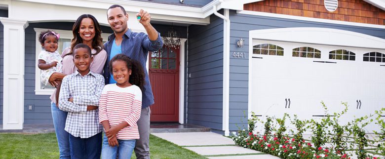 Family of four in front of their home