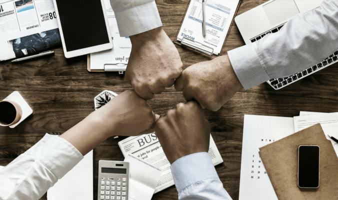 4 hands fist bumping over a conference table