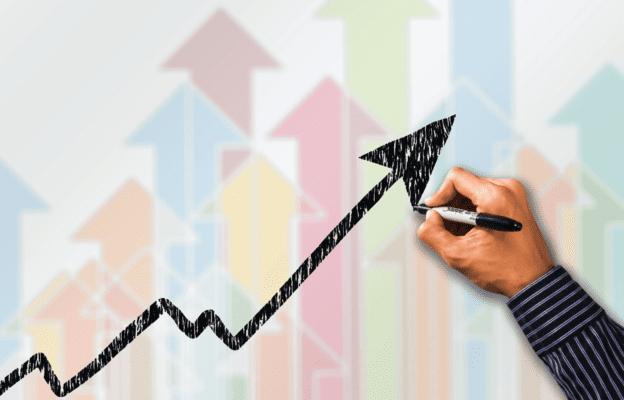 A hand sketches a line graph line with an arrow pointing up. The background is a series of colorful arrows pointing up.